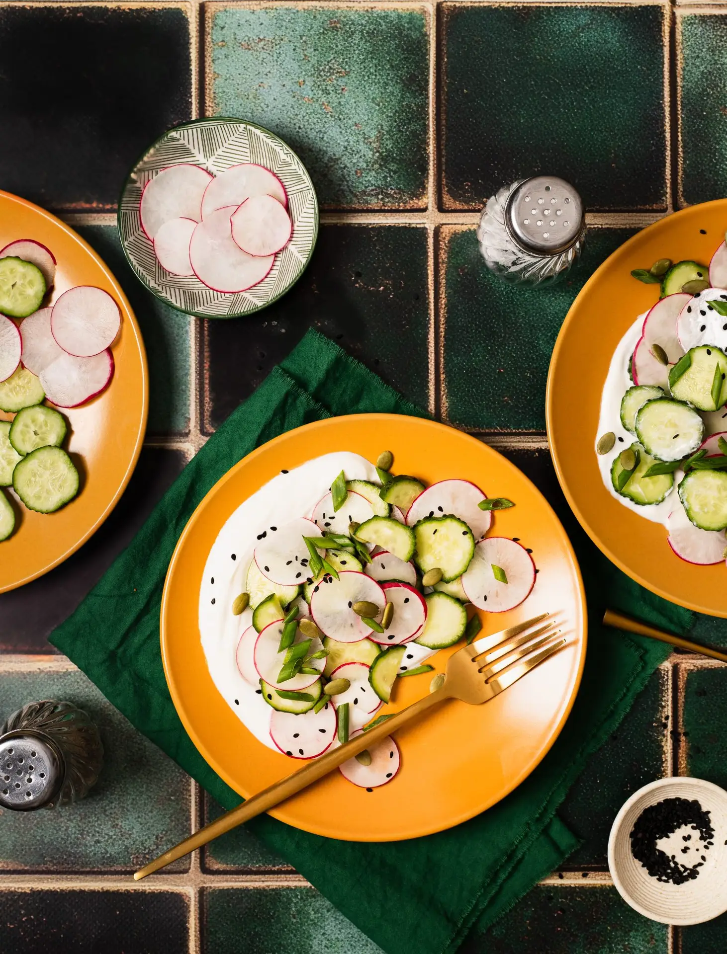 A flat lay of a summer salad on yellow plates on a green background