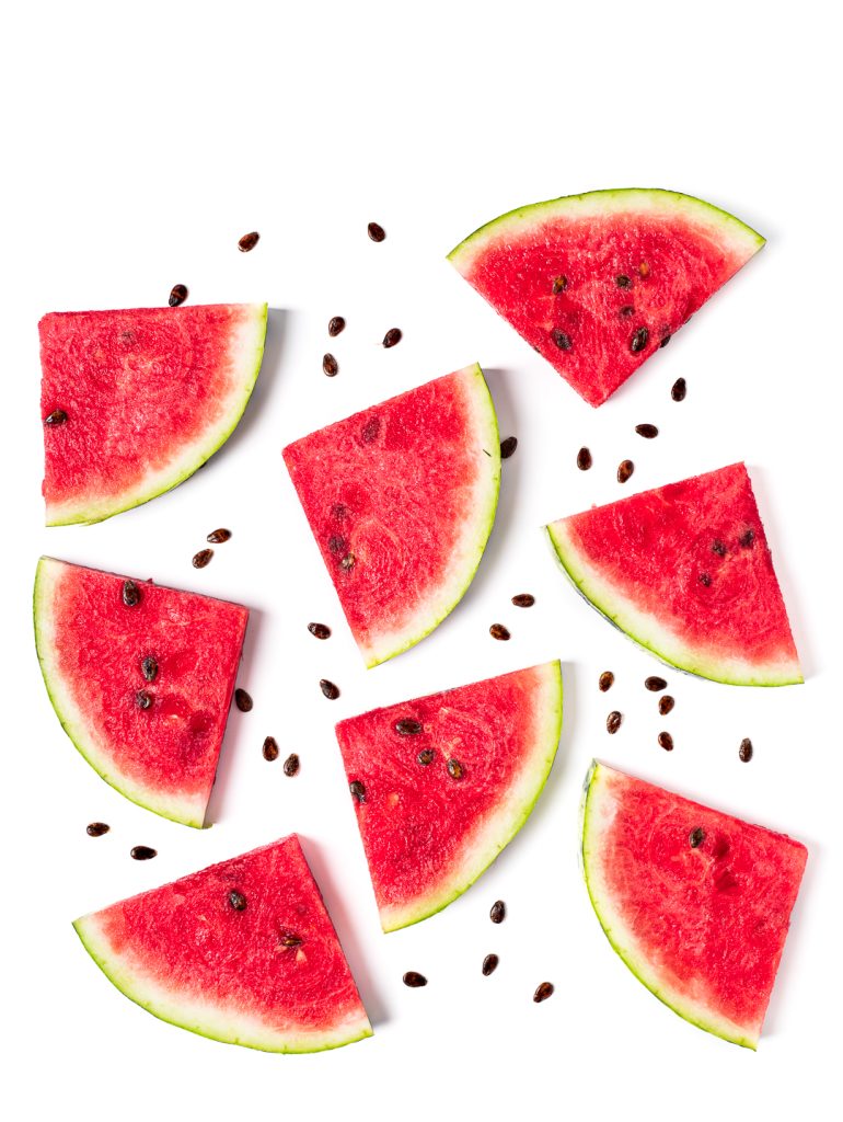Графічний узір із хаотично розкладених шматочків кавуна та насіння кавуна на білому фоні